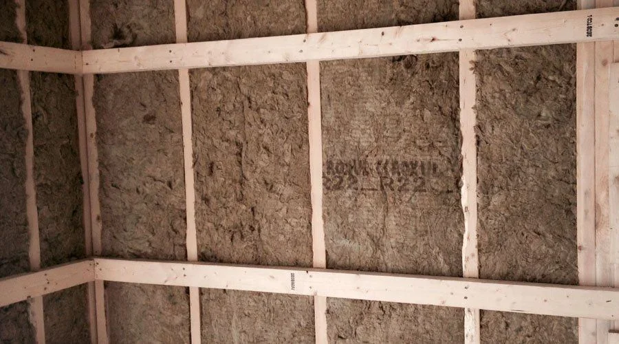 Fiberglass batt insulation installed between wooden wall studs in residential framing