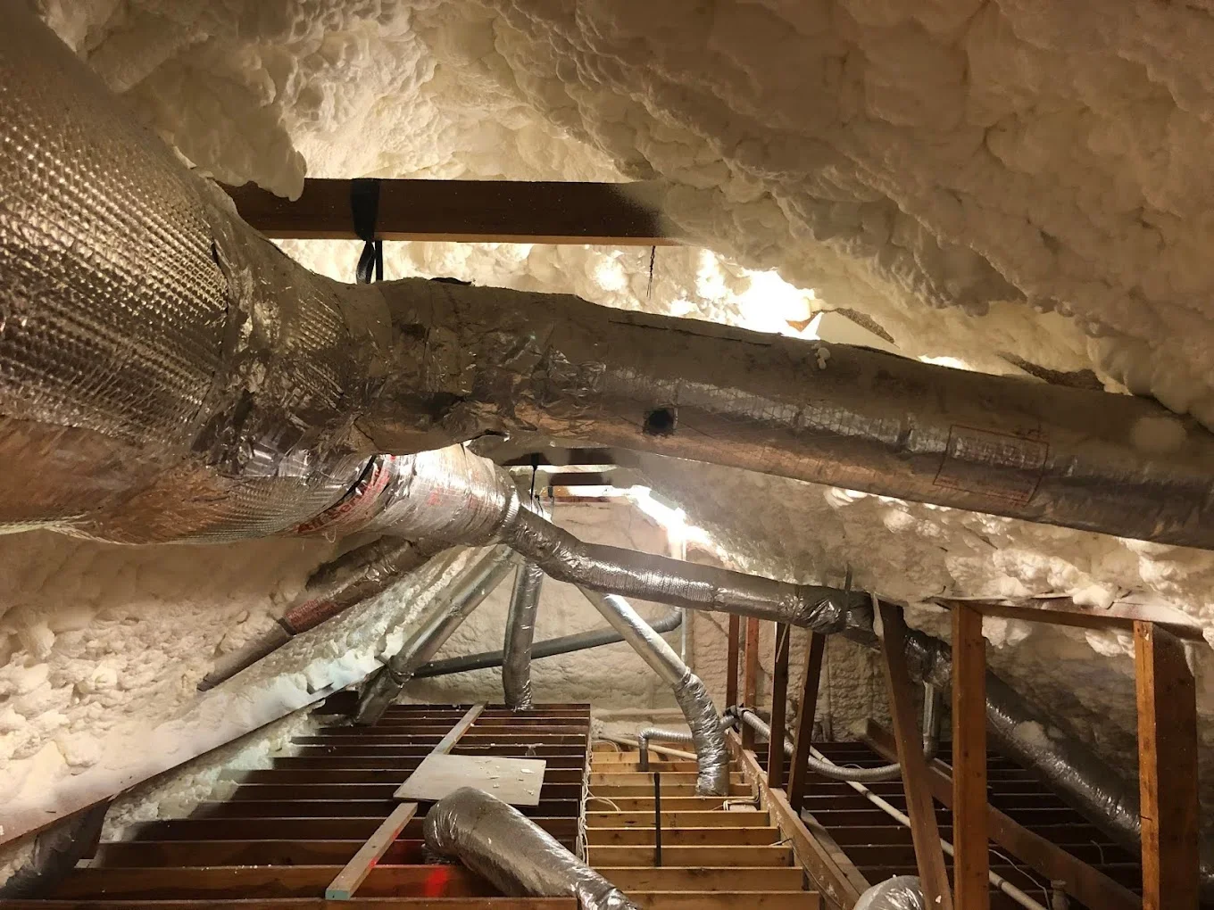 Attic insulation installation with wrapped HVAC ducts and blown-in fiberglass insulation