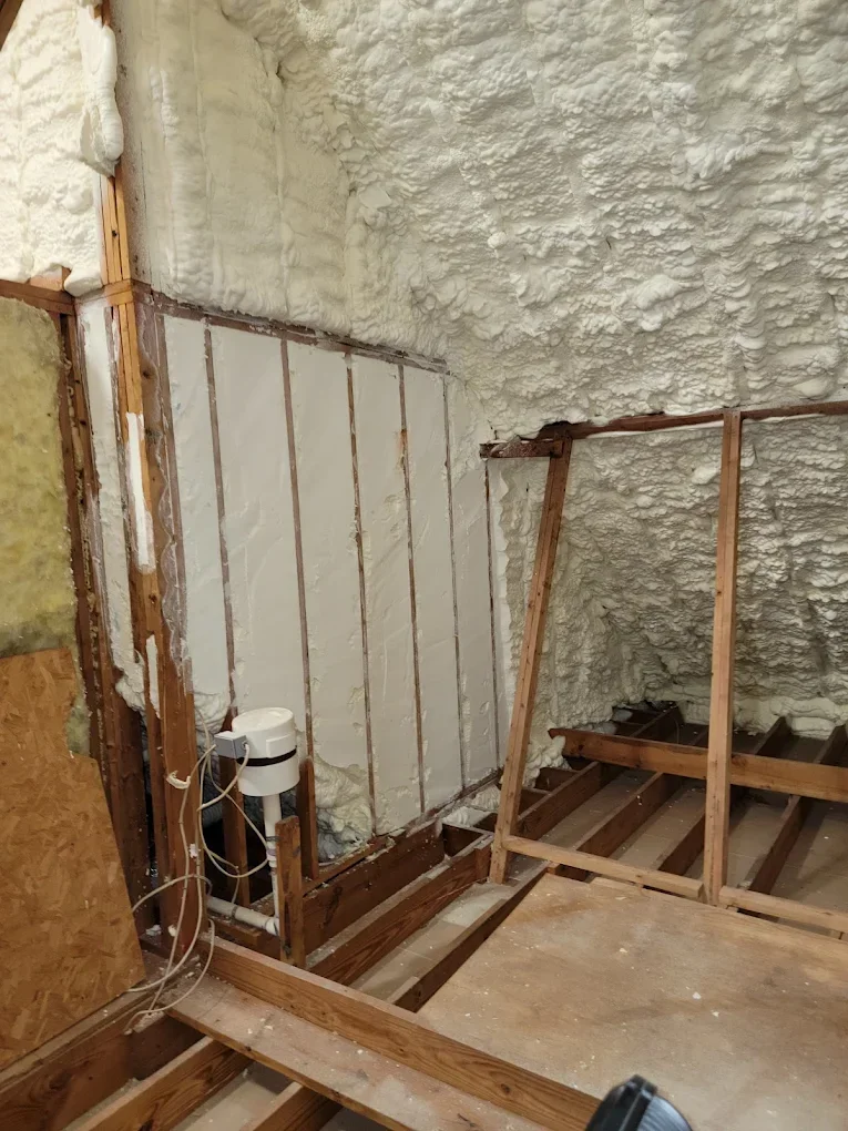 Basement wall with fiberglass insulation batts installed between wooden studs against concrete block foundation
