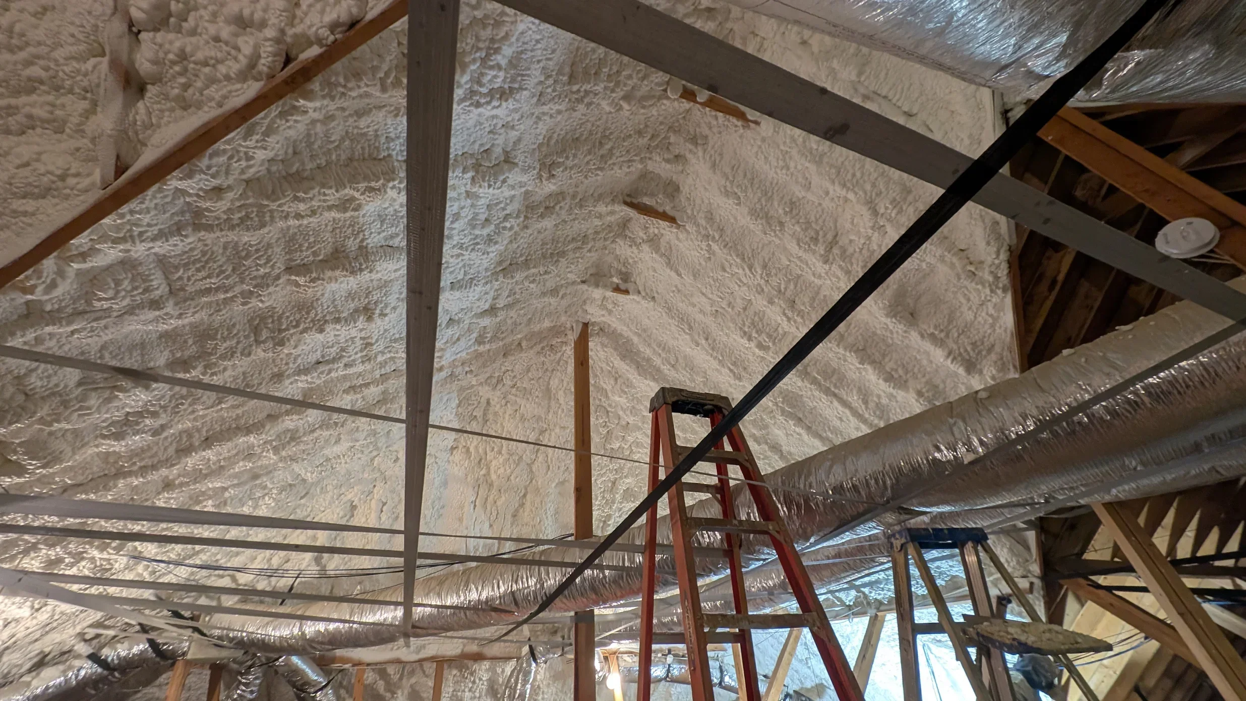 Attic insulation installation with blown-in fiberglass and reflective vapor barriers