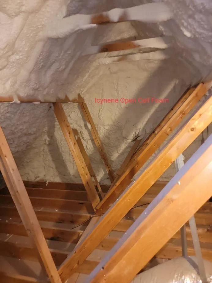 Open cell foam insulation sprayed between attic rafters and wooden framing
