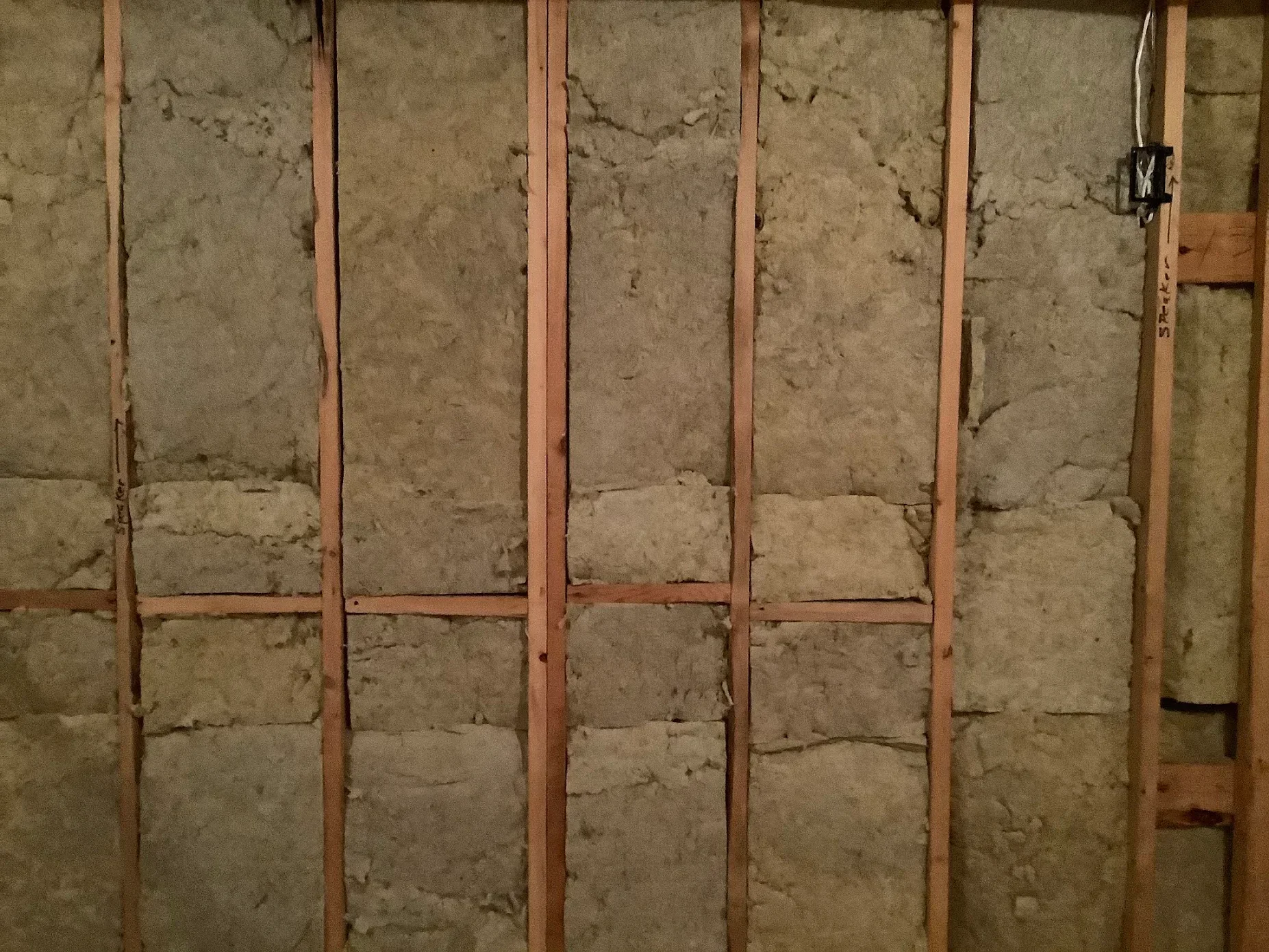 Fiberglass batt insulation installed between wooden wall studs in framed cavity