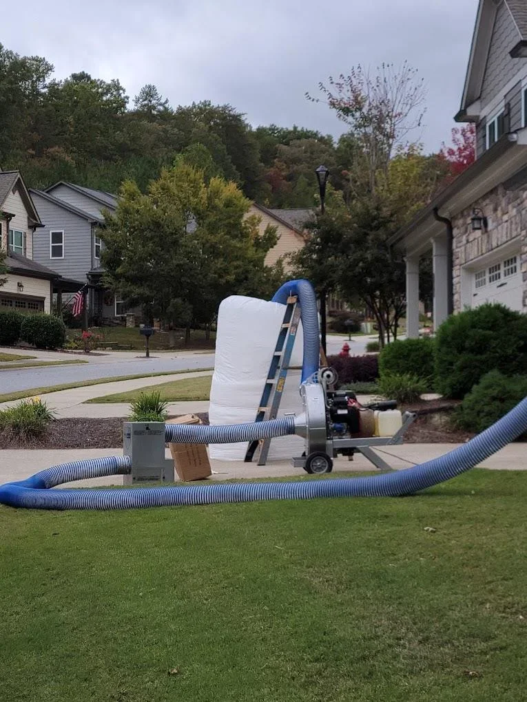 Insulation blower truck with blue hoses installed in residential driveway